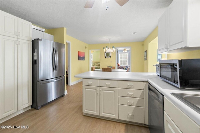 kitchen with appliances with stainless steel finishes, light countertops, light wood-style flooring, and a peninsula