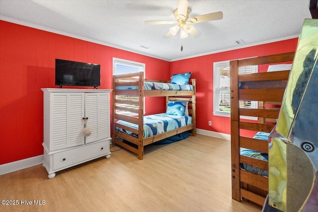 bedroom featuring a textured ceiling, multiple windows, ornamental molding, and wood finished floors