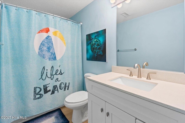 bathroom featuring a textured ceiling, toilet, wood finished floors, vanity, and visible vents