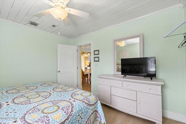 bedroom featuring light wood-style flooring, wood ceiling, a ceiling fan, visible vents, and crown molding