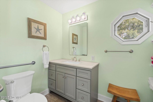 bathroom with baseboards, vanity, toilet, and wood finished floors