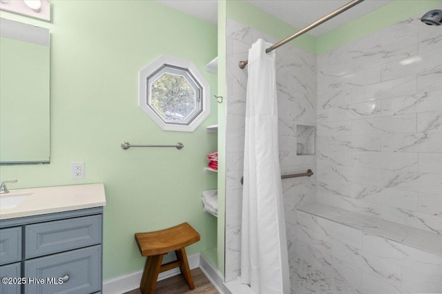 full bath with a stall shower, baseboards, wood finished floors, and vanity