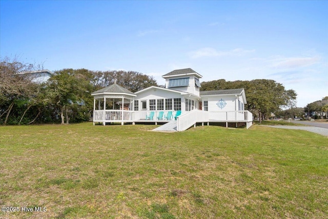 back of property with a deck, a lawn, and a gazebo