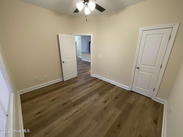 unfurnished bedroom featuring ceiling fan, dark wood finished floors, and baseboards