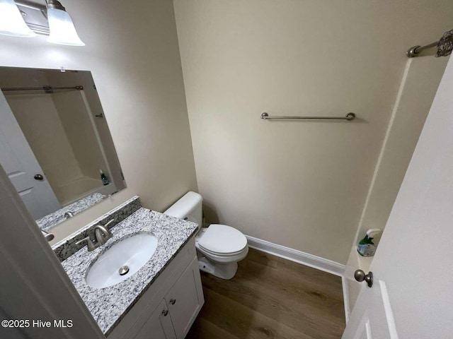 bathroom featuring baseboards, vanity, toilet, and wood finished floors