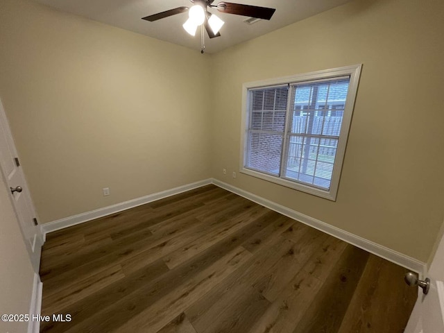 empty room featuring baseboards, dark wood finished floors, and a ceiling fan