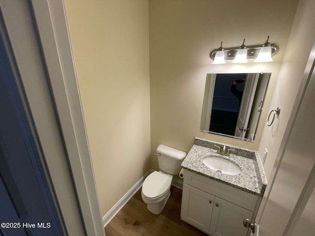 bathroom with baseboards, vanity, toilet, and wood finished floors