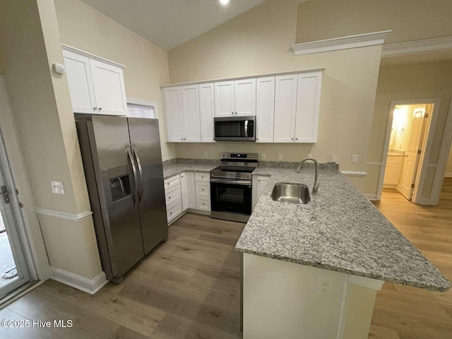 kitchen with stainless steel appliances, a peninsula, a sink, white cabinets, and light stone countertops