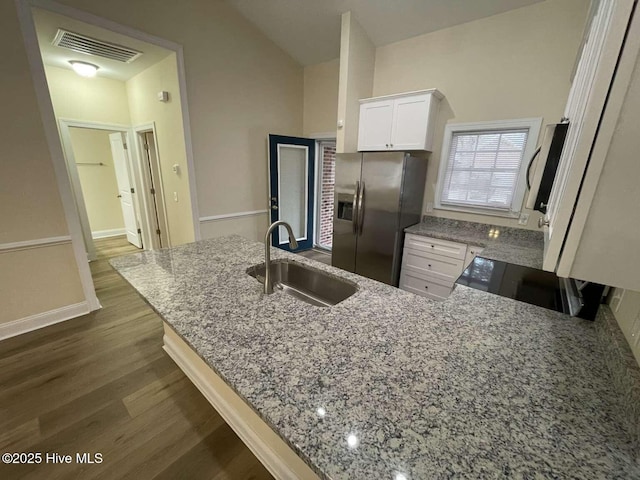 kitchen with stove, a sink, visible vents, stainless steel fridge with ice dispenser, and light stone countertops