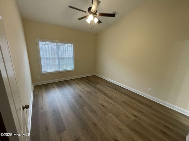 empty room featuring a ceiling fan, dark wood finished floors, and baseboards