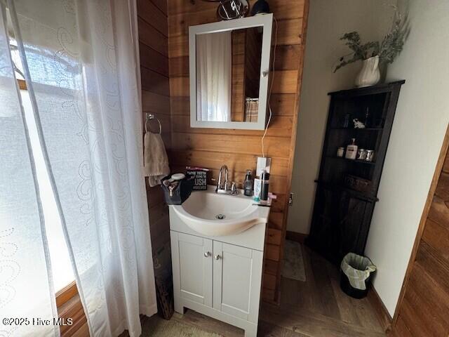 bathroom with wood finished floors, vanity, and wooden walls