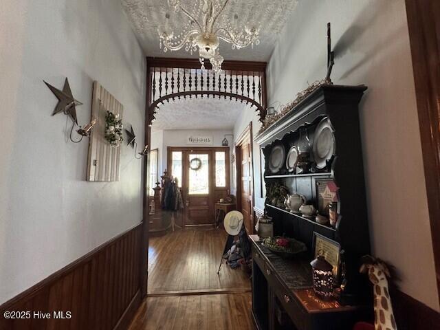 entryway with hardwood / wood-style flooring, wooden walls, a notable chandelier, and wainscoting