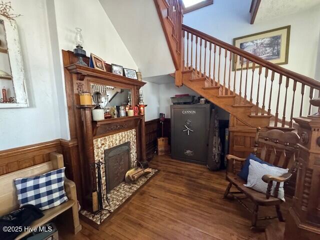 sitting room featuring stairway, wainscoting, wood finished floors, and a tile fireplace