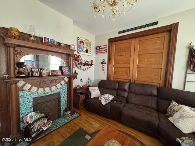 living area with a premium fireplace, wood finished floors, and an inviting chandelier