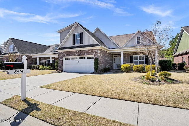 craftsman-style house with a front lawn, board and batten siding, concrete driveway, an attached garage, and brick siding