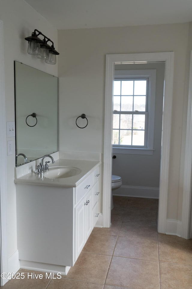 bathroom featuring tile patterned flooring, baseboards, vanity, and toilet