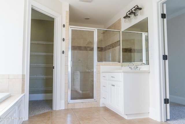 bathroom featuring tile patterned floors, a shower stall, a spacious closet, and vanity