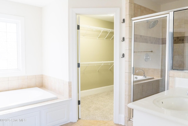 full bathroom featuring a spacious closet, a stall shower, a sink, and a bath