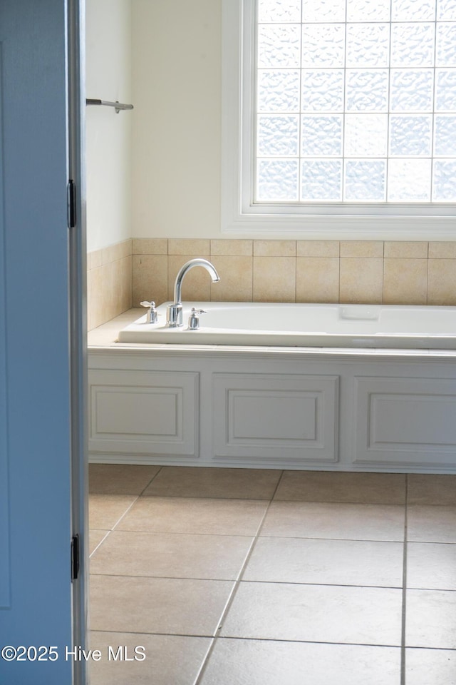 bathroom featuring tile patterned floors, a bath, and a healthy amount of sunlight