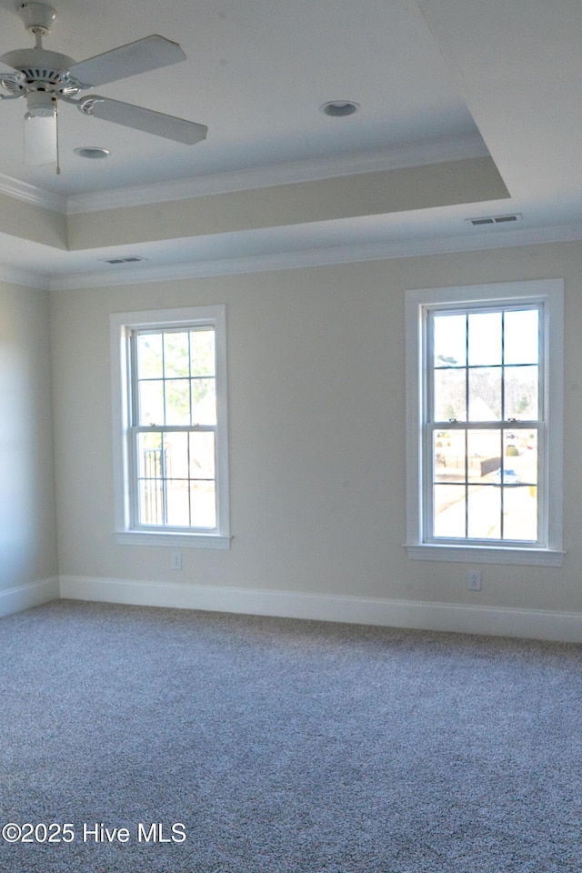 spare room with ornamental molding, a raised ceiling, and visible vents