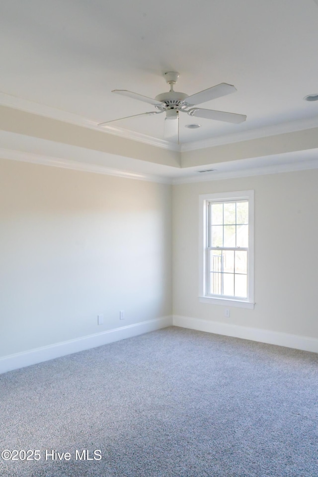 empty room featuring baseboards, ceiling fan, ornamental molding, a tray ceiling, and carpet flooring