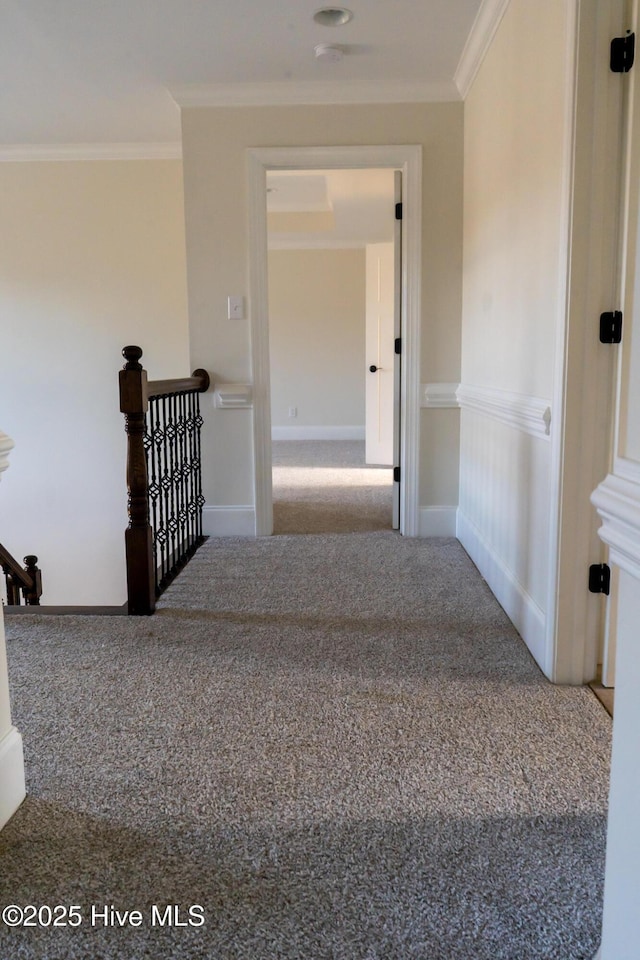 hall featuring carpet floors, baseboards, crown molding, and an upstairs landing