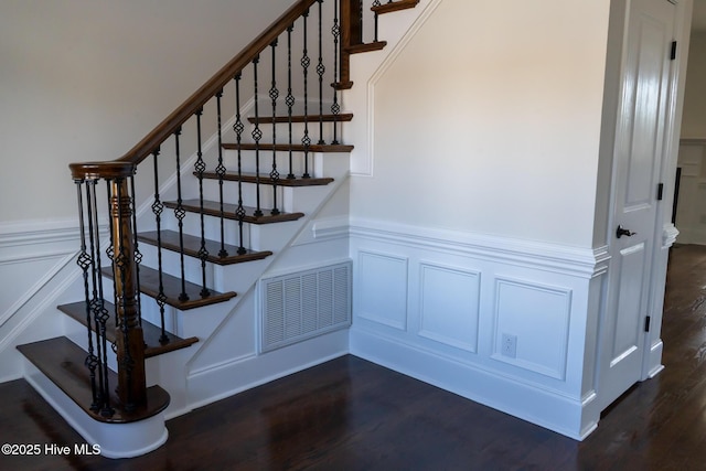 stairway featuring a wainscoted wall, wood finished floors, visible vents, and a decorative wall