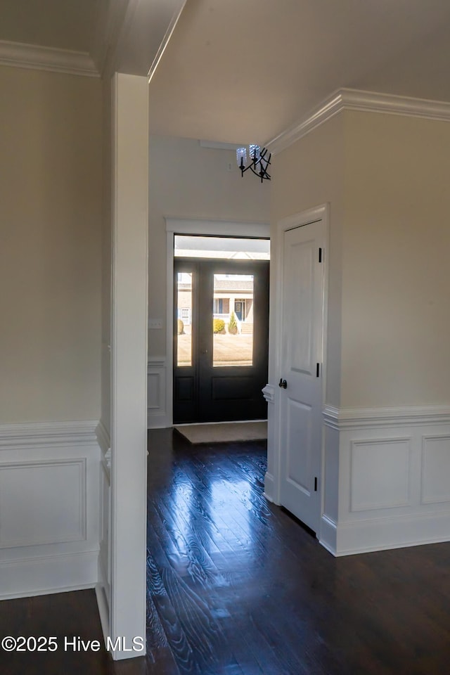 entrance foyer featuring a wainscoted wall, a notable chandelier, crown molding, and wood finished floors