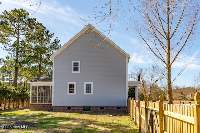 view of home's exterior with a yard, crawl space, fence, and a sunroom