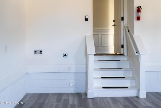 stairs with wainscoting and wood finished floors