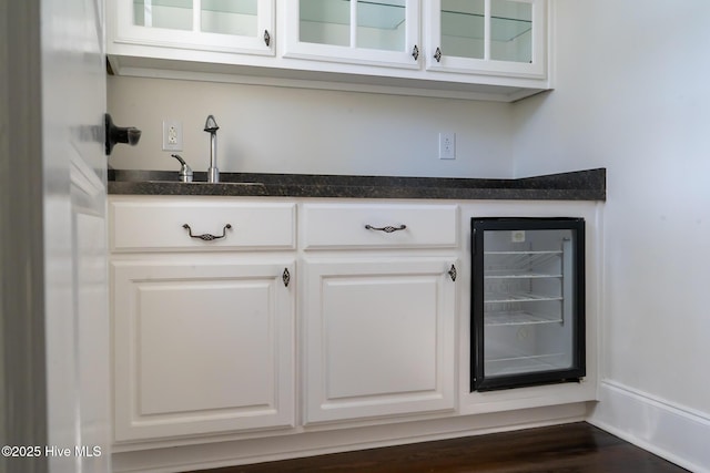 bar with dark wood finished floors, wine cooler, indoor wet bar, and a sink