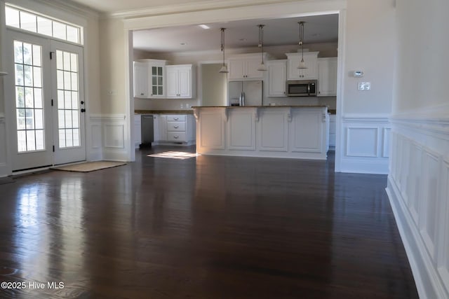 kitchen with stainless steel appliances, ornamental molding, white cabinetry, and a healthy amount of sunlight