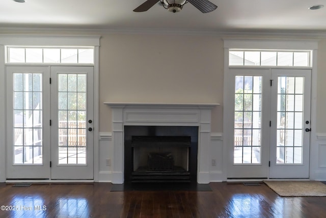 doorway to outside with a healthy amount of sunlight, a fireplace with flush hearth, dark wood finished floors, and crown molding