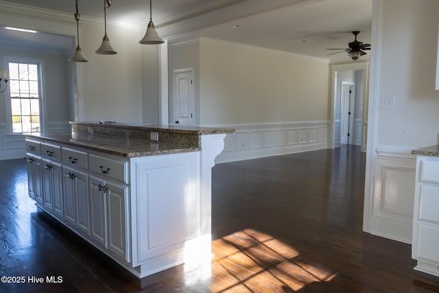 kitchen featuring a center island, dark wood-style flooring, crown molding, hanging light fixtures, and wainscoting