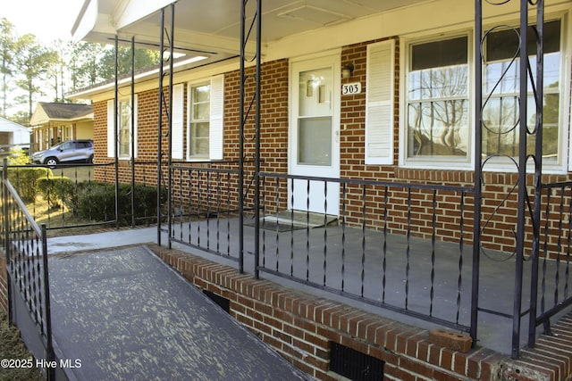 property entrance featuring a porch and brick siding