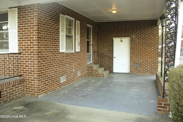 entrance to property featuring crawl space and brick siding