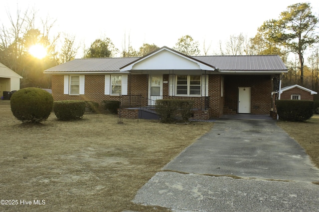 ranch-style house featuring metal roof, brick siding, and a porch