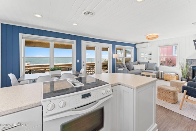 kitchen featuring open floor plan, white range with electric cooktop, a wall mounted AC, and a healthy amount of sunlight