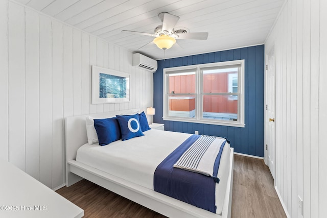 bedroom featuring ceiling fan, an AC wall unit, wood finished floors, and baseboards