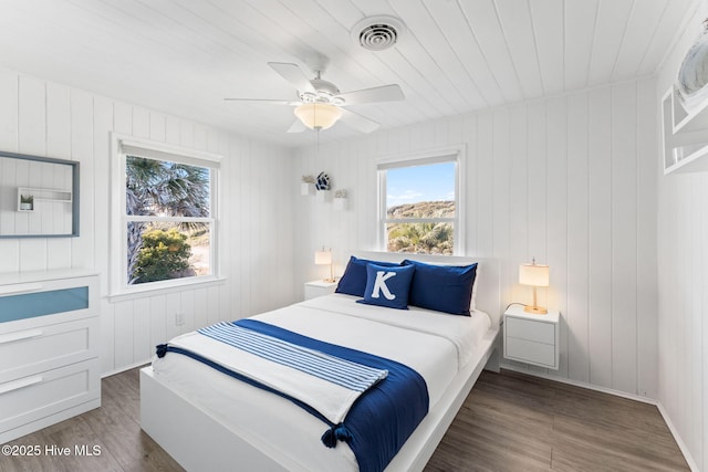 bedroom featuring ceiling fan, wood finished floors, visible vents, and baseboards