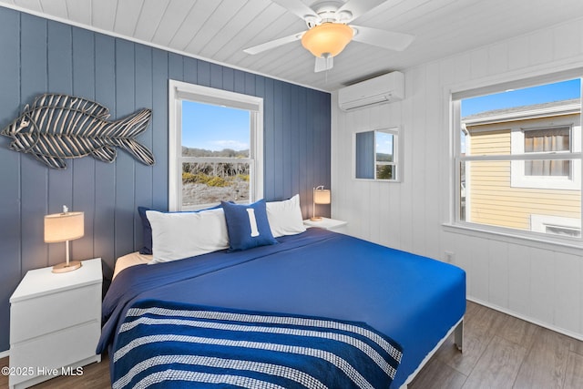 bedroom featuring a wall unit AC, a ceiling fan, and wood finished floors