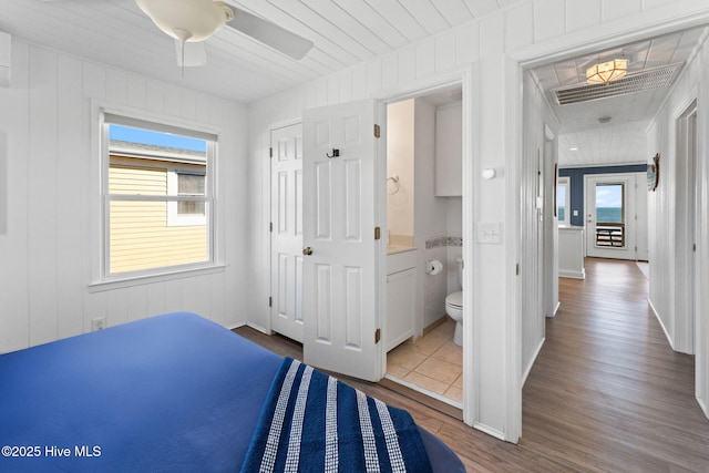 bedroom featuring ensuite bath, wood finished floors, and visible vents