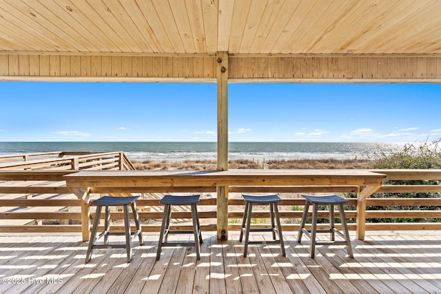 wooden terrace featuring a water view and a view of the beach