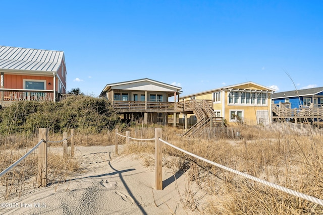 rear view of house with a standing seam roof, stairway, metal roof, and a wooden deck