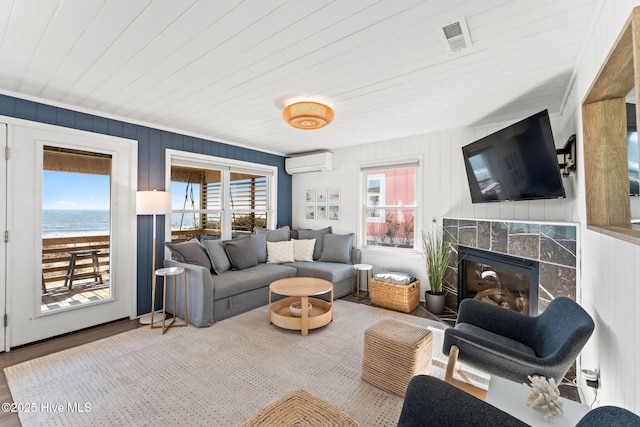 living area featuring a fireplace, wood finished floors, wood ceiling, a water view, and an AC wall unit