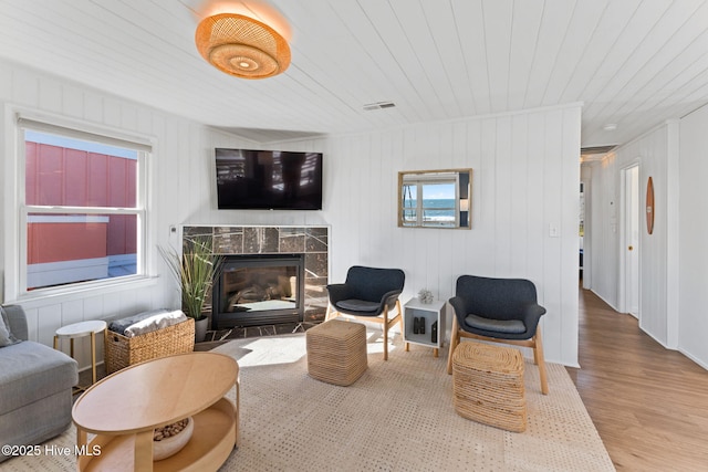 living area with wooden ceiling, visible vents, wood finished floors, and a high end fireplace