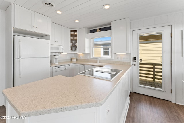 kitchen featuring dark wood finished floors, visible vents, glass insert cabinets, white cabinets, and white appliances