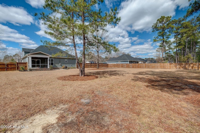 view of yard featuring a sunroom and a fenced backyard