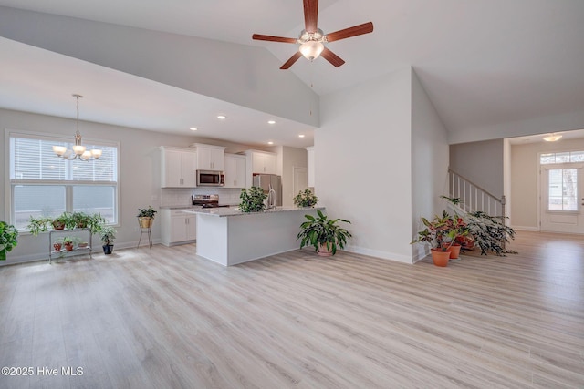 kitchen with hanging light fixtures, light wood-style floors, white cabinetry, and appliances with stainless steel finishes