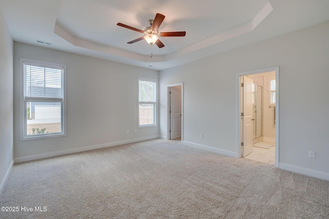 empty room featuring light carpet, baseboards, visible vents, and a tray ceiling